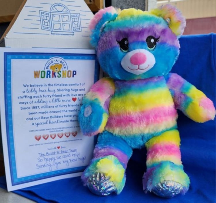 Rainbow Sparkle Teddy Bear alongside a note from Build-a-Bear, replacing a little girl's toy